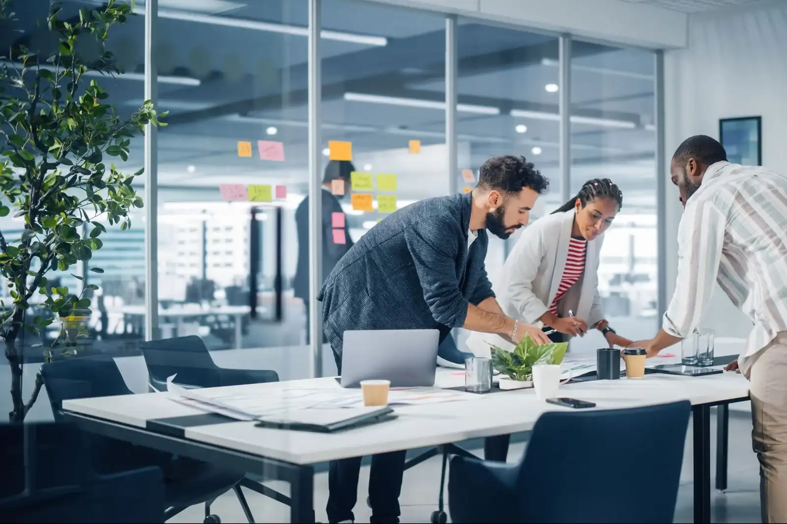 Three colleagues collaborating on a project in a glass-walled office